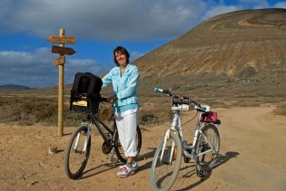 Claudia mit Fahrrad vor einem mehrfarbigen vulkanischen Berg